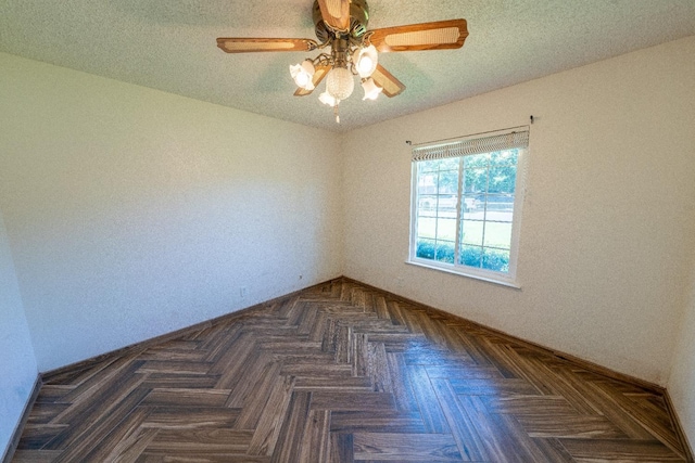 unfurnished room featuring dark parquet flooring, ceiling fan, and a textured ceiling