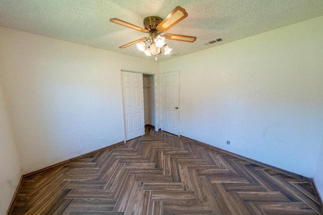 unfurnished bedroom featuring a textured ceiling, dark parquet floors, a closet, and ceiling fan