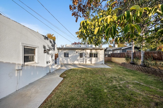 back of property with a yard, an outbuilding, and a patio area