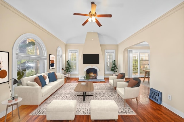 living room featuring ornamental molding, hardwood / wood-style flooring, ceiling fan, a fireplace, and a high ceiling