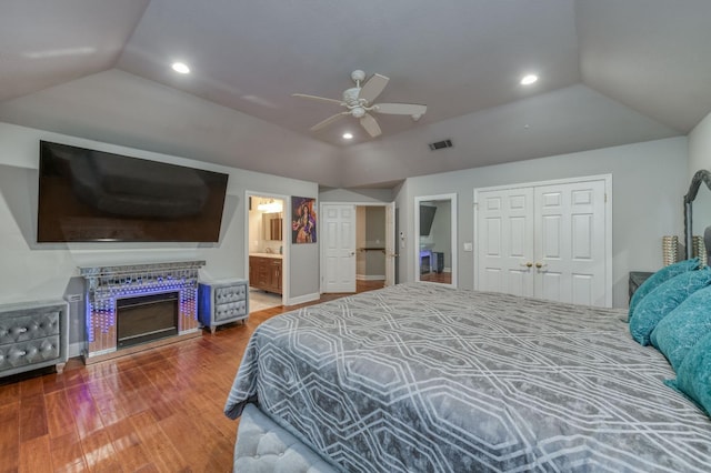 bedroom with connected bathroom, ceiling fan, wood-type flooring, lofted ceiling, and a closet