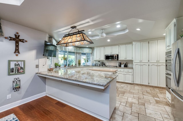 kitchen featuring decorative light fixtures, white cabinetry, kitchen peninsula, and appliances with stainless steel finishes