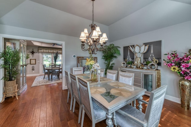 dining room featuring hardwood / wood-style flooring, ceiling fan with notable chandelier, and vaulted ceiling