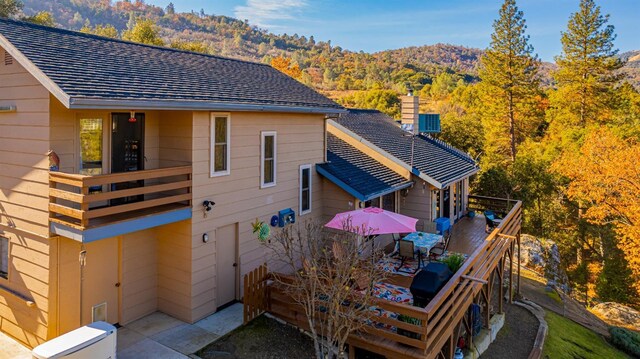 back of property with a mountain view, a patio, and a balcony