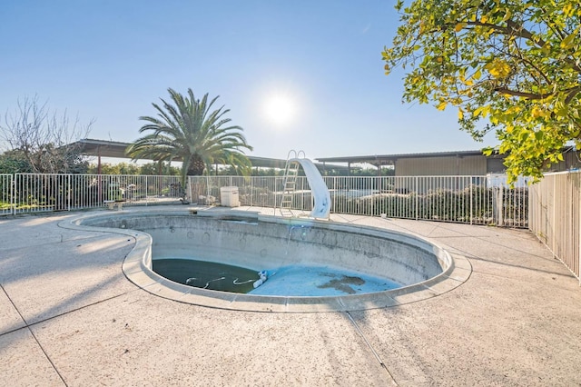view of swimming pool featuring a water slide and a hot tub