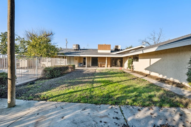 back of house with central AC and a lawn