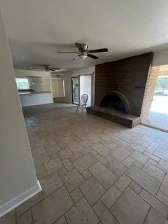 unfurnished living room featuring ceiling fan and a large fireplace