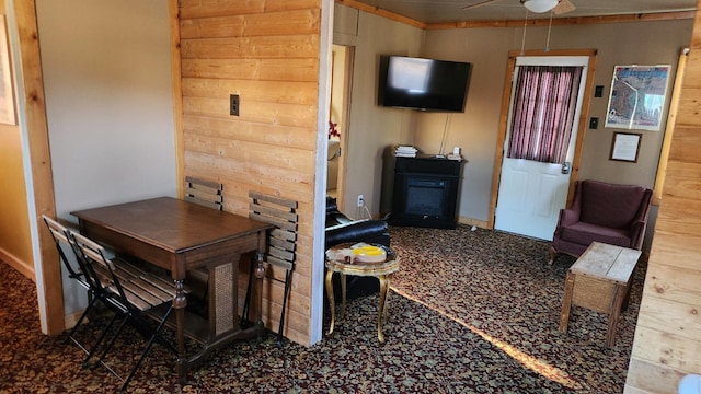 dining space with carpet floors, ceiling fan, and wood walls