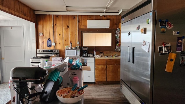 kitchen featuring wood walls, dark wood-type flooring, stainless steel appliances, and a wall mounted AC