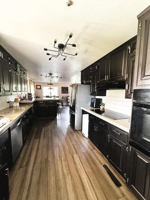 kitchen with kitchen peninsula, a chandelier, a textured ceiling, black appliances, and hardwood / wood-style flooring