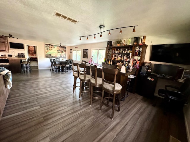 bar with a textured ceiling and dark wood-type flooring