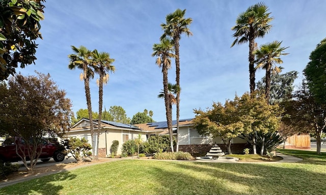 view of front facade with a front lawn and solar panels