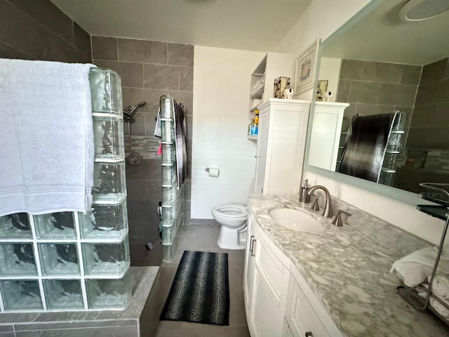 bathroom with vanity, toilet, and tiled shower