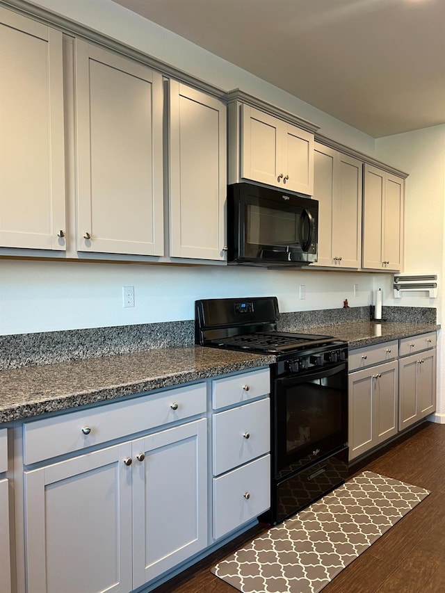 kitchen featuring dark hardwood / wood-style flooring, gray cabinets, black range, and dark stone countertops