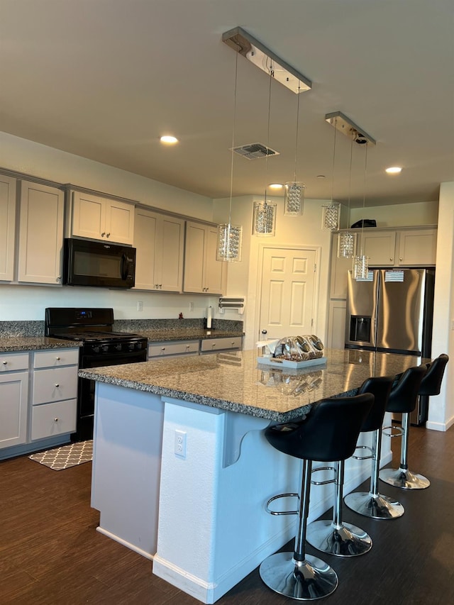 kitchen with dark hardwood / wood-style flooring, a center island, black appliances, and decorative light fixtures