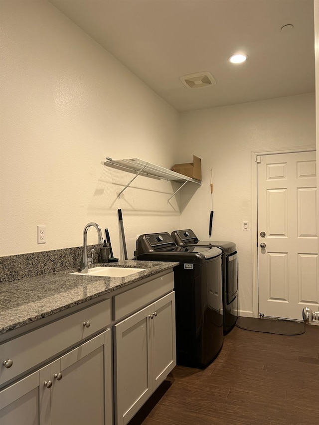 clothes washing area featuring dark hardwood / wood-style flooring, sink, cabinets, and washing machine and dryer