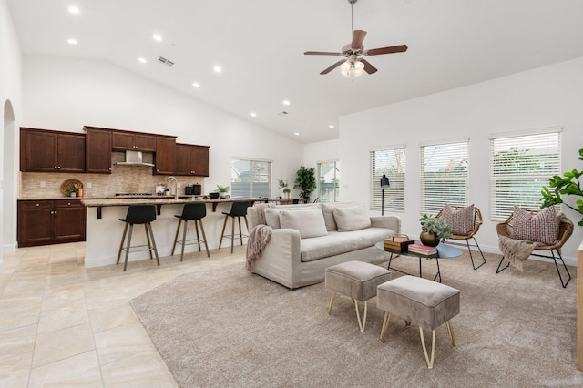 living room with light tile patterned floors, high vaulted ceiling, ceiling fan, and sink