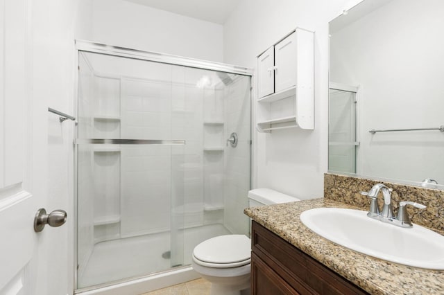 bathroom featuring tile patterned floors, vanity, toilet, and a shower with door