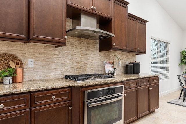 kitchen featuring light stone countertops, stainless steel appliances, tasteful backsplash, lofted ceiling, and dark brown cabinets