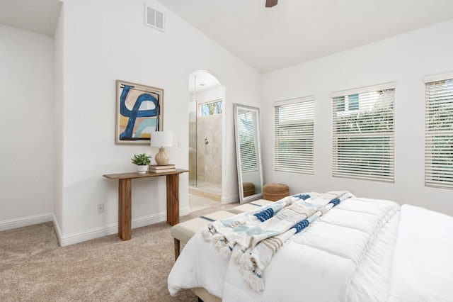 carpeted bedroom featuring vaulted ceiling, ensuite bath, and ceiling fan