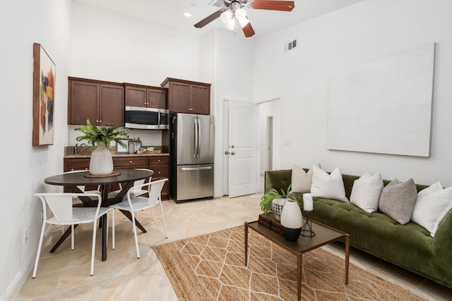 living room with a towering ceiling and ceiling fan