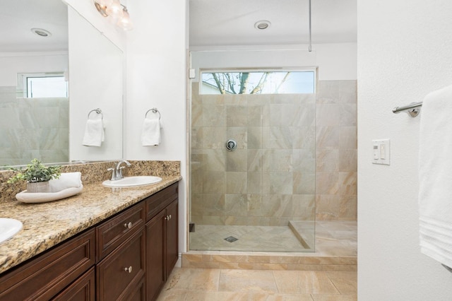 bathroom featuring a wealth of natural light, tile patterned flooring, vanity, and tiled shower