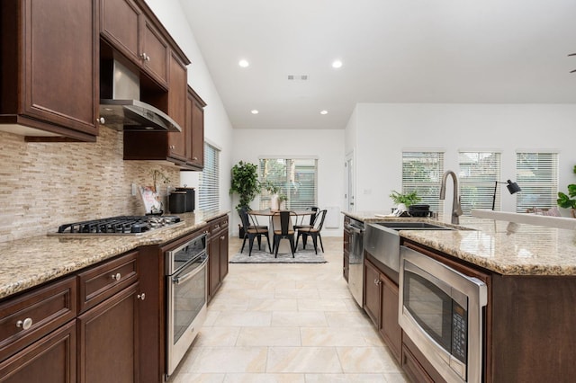 kitchen with stainless steel appliances, light stone counters, tasteful backsplash, and a healthy amount of sunlight