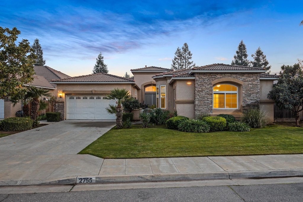 mediterranean / spanish-style house featuring a lawn and a garage