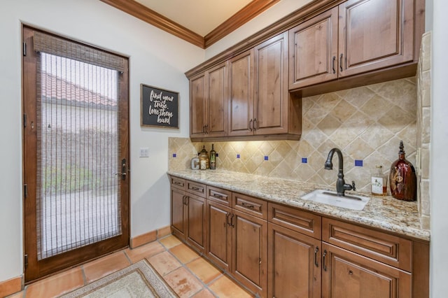 kitchen with light stone countertops, sink, tasteful backsplash, light tile patterned floors, and ornamental molding