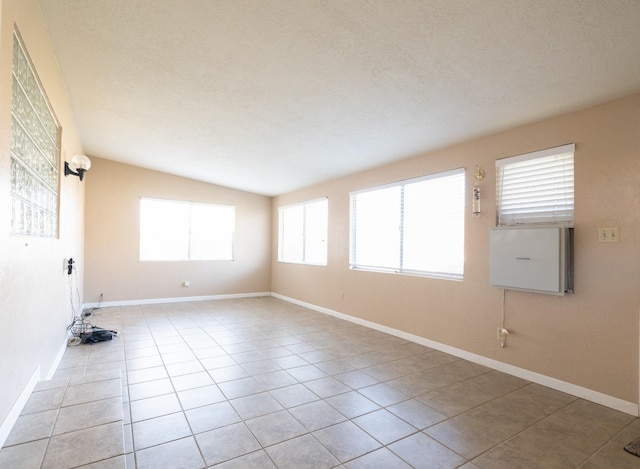 spare room featuring light tile patterned flooring, a textured ceiling, and baseboards