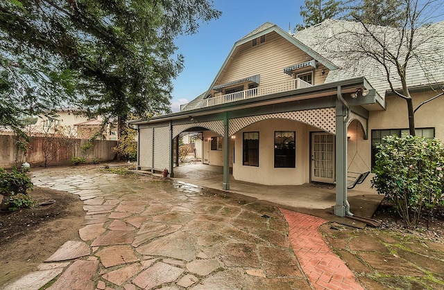 back of house featuring fence, a patio area, a balcony, and stucco siding