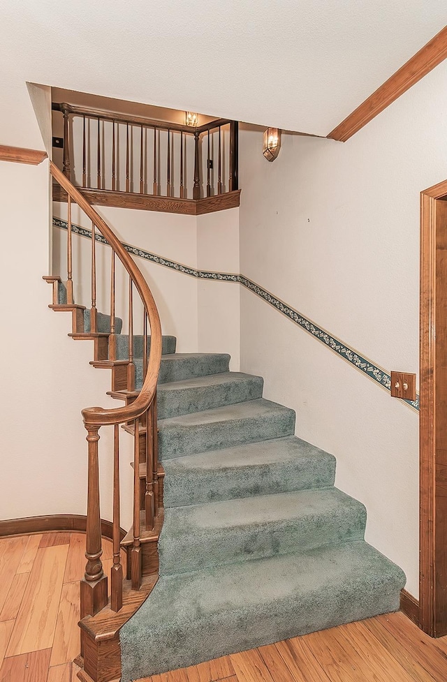 staircase featuring wood finished floors and baseboards