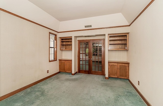 spare room featuring built in shelves, french doors, vaulted ceiling, light carpet, and ornamental molding