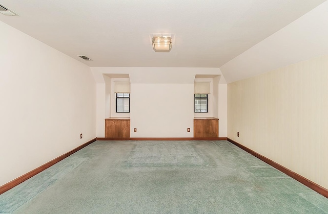 carpeted spare room featuring vaulted ceiling