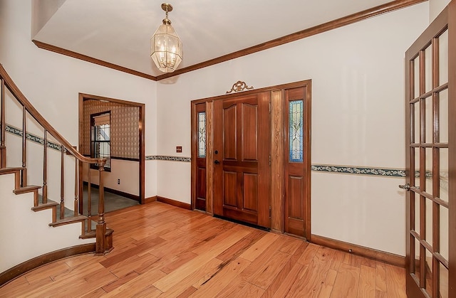 foyer with a notable chandelier, light hardwood / wood-style floors, and crown molding