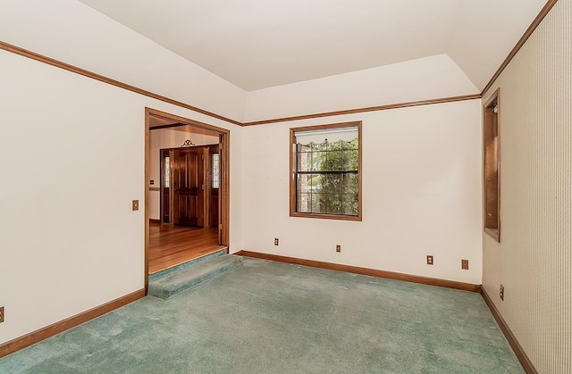 carpeted spare room with vaulted ceiling and baseboards
