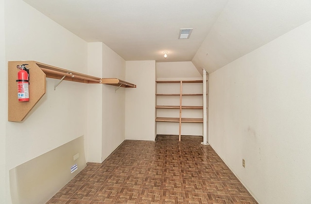 spacious closet with dark parquet flooring and lofted ceiling