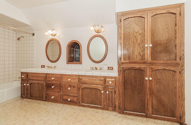 bathroom with vanity, tiled shower / bath, and lofted ceiling