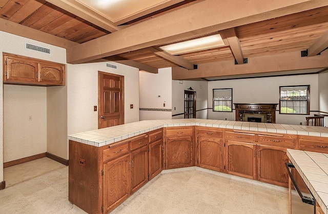 kitchen with kitchen peninsula, beam ceiling, tile countertops, and wood ceiling