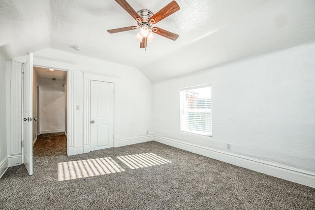 unfurnished bedroom featuring a textured ceiling, ceiling fan, dark carpet, and vaulted ceiling