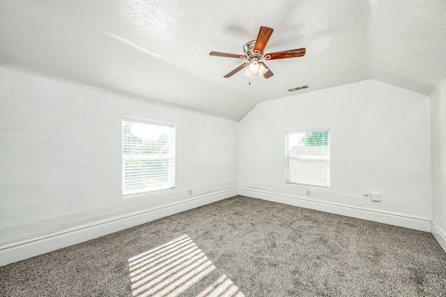 carpeted spare room with a textured ceiling, a wealth of natural light, and lofted ceiling