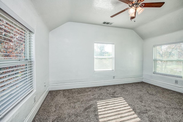 carpeted empty room with a textured ceiling, vaulted ceiling, and ceiling fan