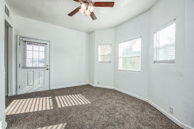 carpeted empty room featuring a textured ceiling, plenty of natural light, and ceiling fan