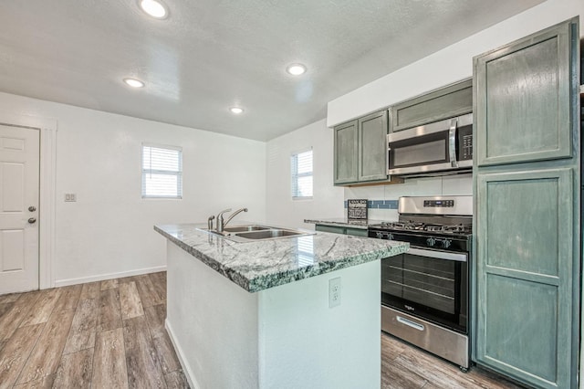 kitchen featuring a center island with sink, sink, stainless steel appliances, and a wealth of natural light