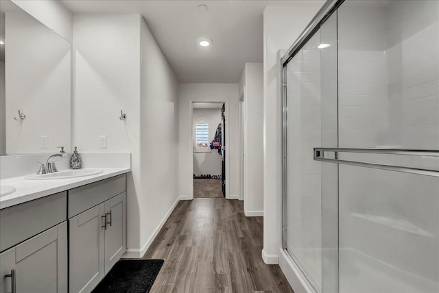 bathroom featuring wood-type flooring, a shower with door, and vanity