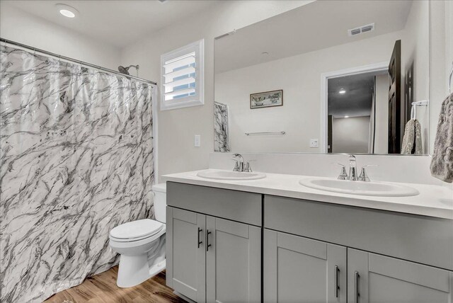 bathroom featuring wood-type flooring, toilet, vanity, and walk in shower