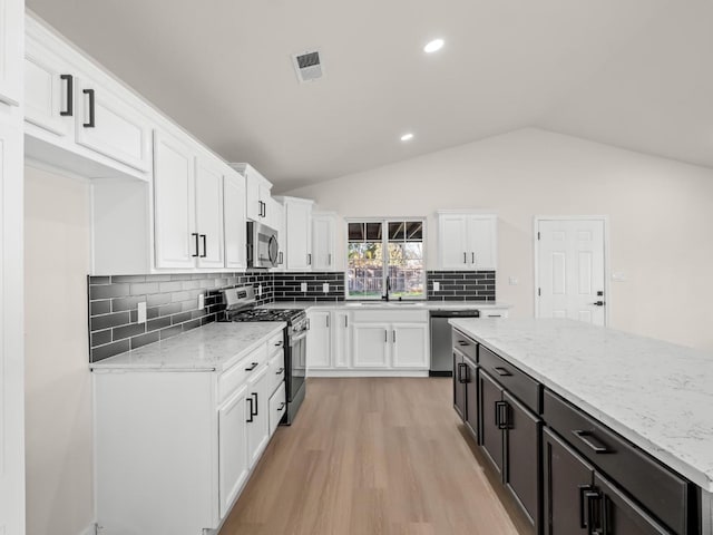 kitchen featuring vaulted ceiling, appliances with stainless steel finishes, white cabinetry, and sink