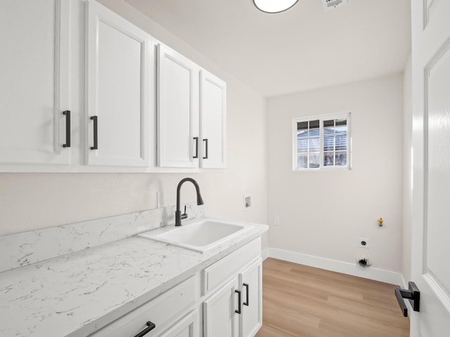 washroom featuring light wood-type flooring, cabinets, electric dryer hookup, and sink