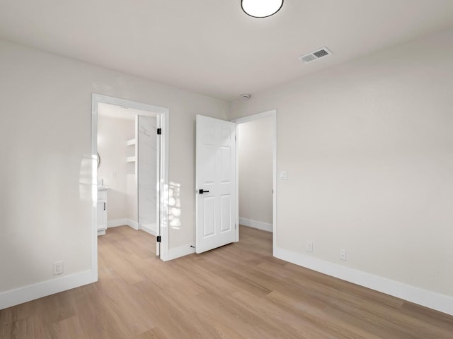 unfurnished bedroom featuring a closet, a walk in closet, and light wood-type flooring