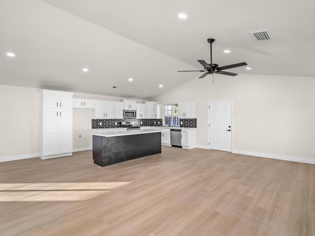 kitchen featuring white cabinetry, appliances with stainless steel finishes, vaulted ceiling, light hardwood / wood-style flooring, and a center island